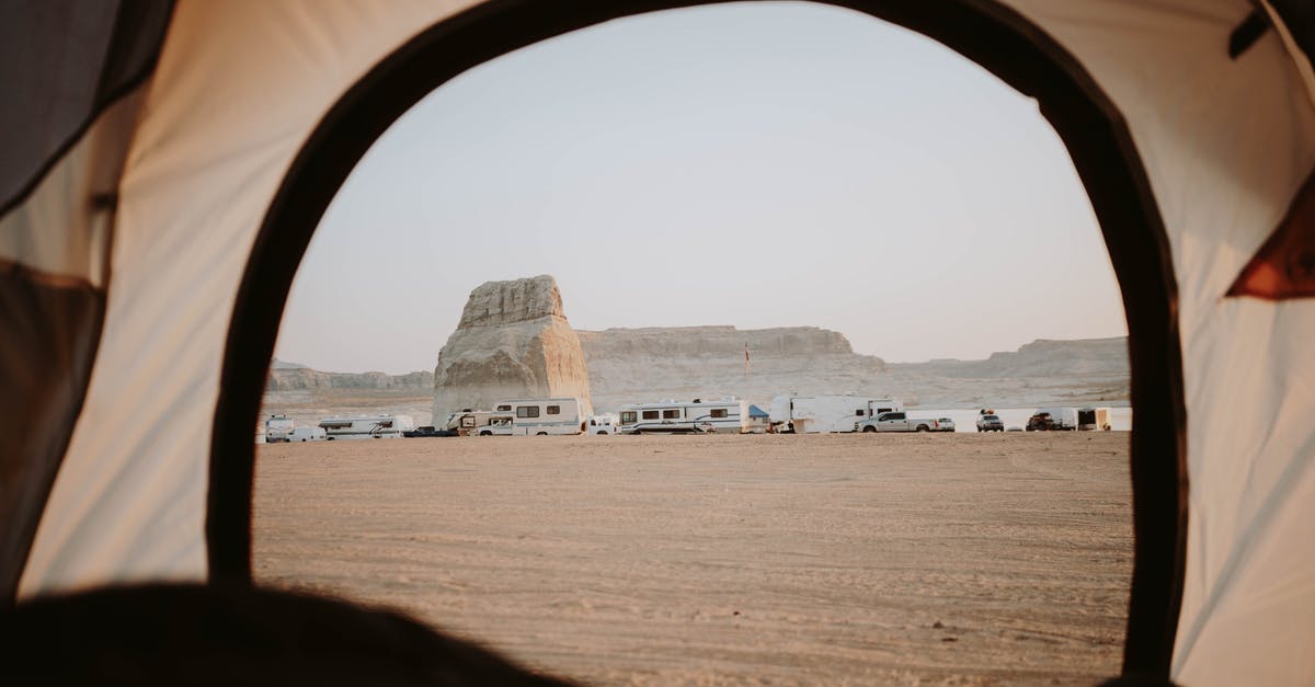 Microwave door blew open when boiling water-vinegar mixture for cleaning - View of sandy beach with distanced cars parked on seaside with rocky cliffs through opened tent in nature with cloudless sky