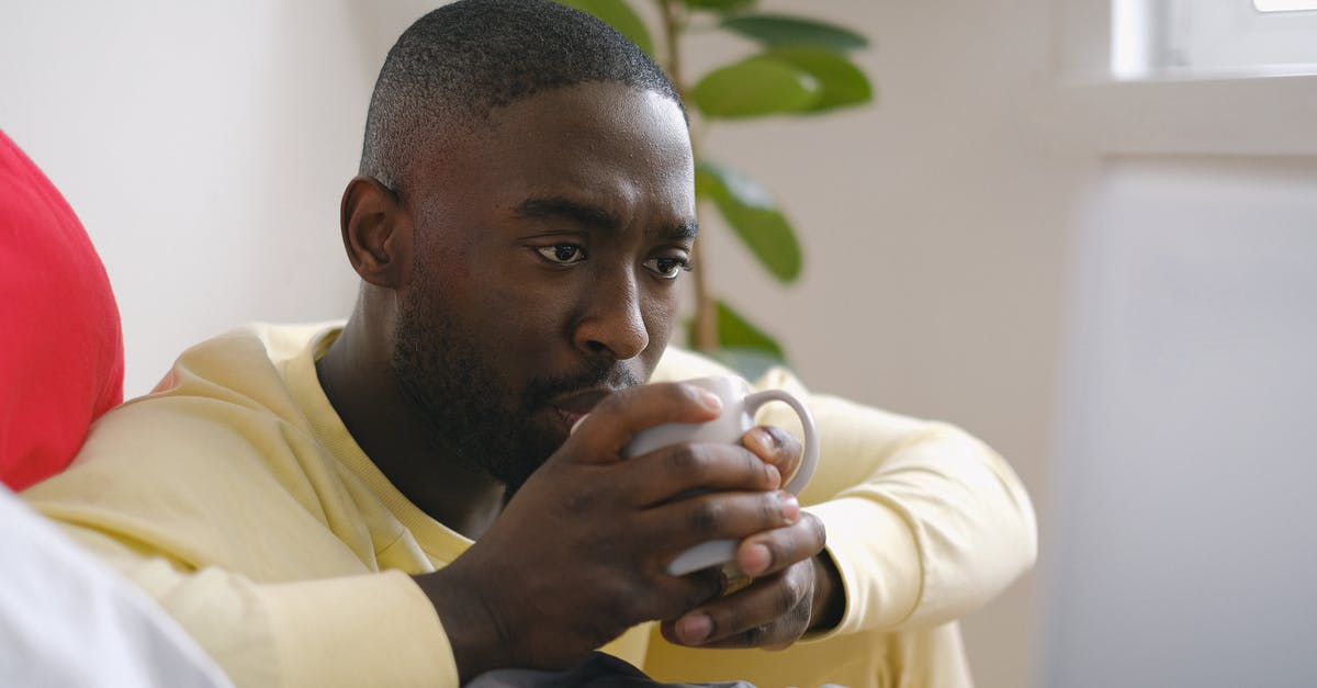 Minimum amount of oil that should be used in deep fryer - Attentive black man drinking coffee against laptop on bed