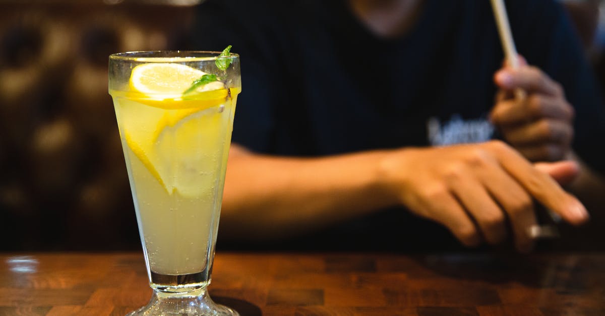 Mint vs Peppermint - Crop faceless man sitting at table with fresh citrus lemonade