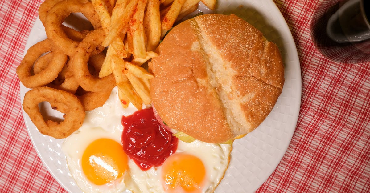 mixed egg and bicarbonate of soda - Top view of delicious hamburger with French fires and onion rings served on plate with eggs and ketchup near glass of coke