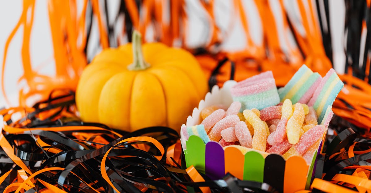 Mixing starches with sugar to make chewy candies - Assorted Chewy Candies in a Container Beside a Pumpkin
