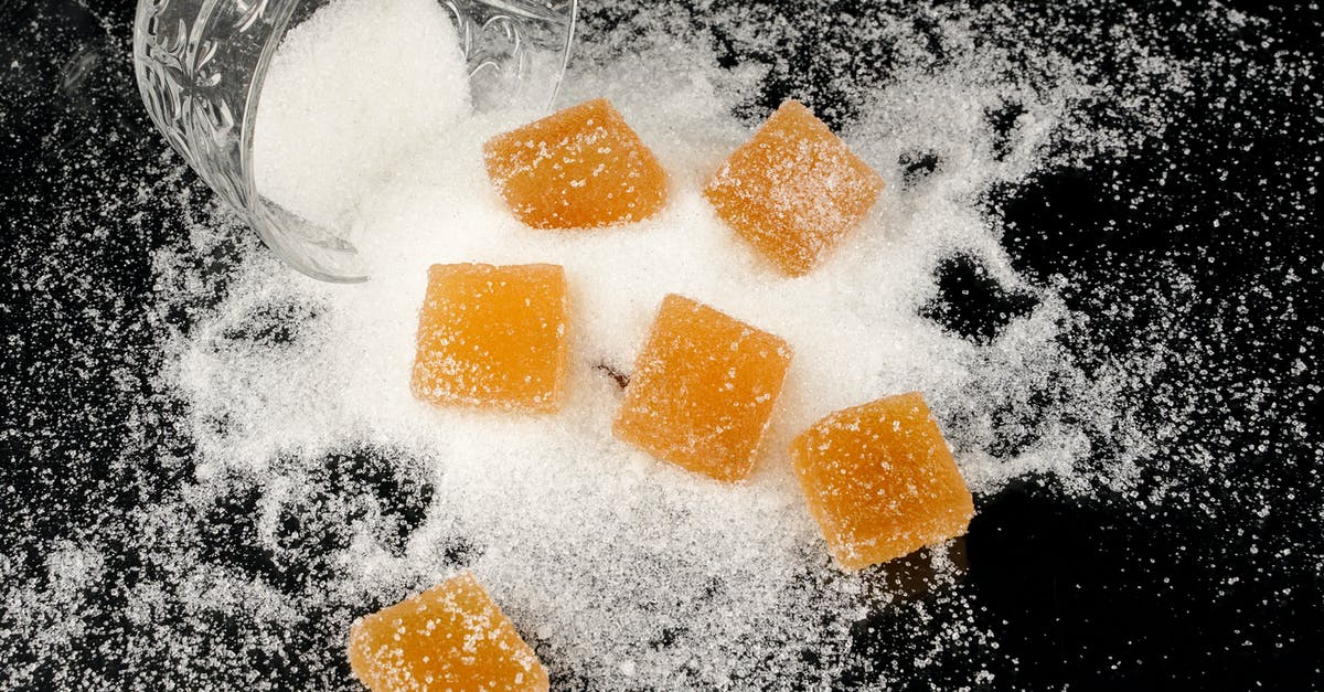 Mixing starches with sugar to make chewy candies - Sugar Coated Yellow Square Candies on a Black Surface with Sugar