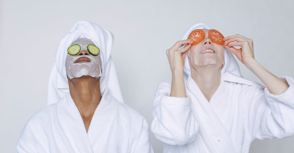 Moisture in Vegetable Bin - Young multiethnic females wearing bathrobes and towels moisturizing face with masks and slices of tomatoes and cucumbers against white background