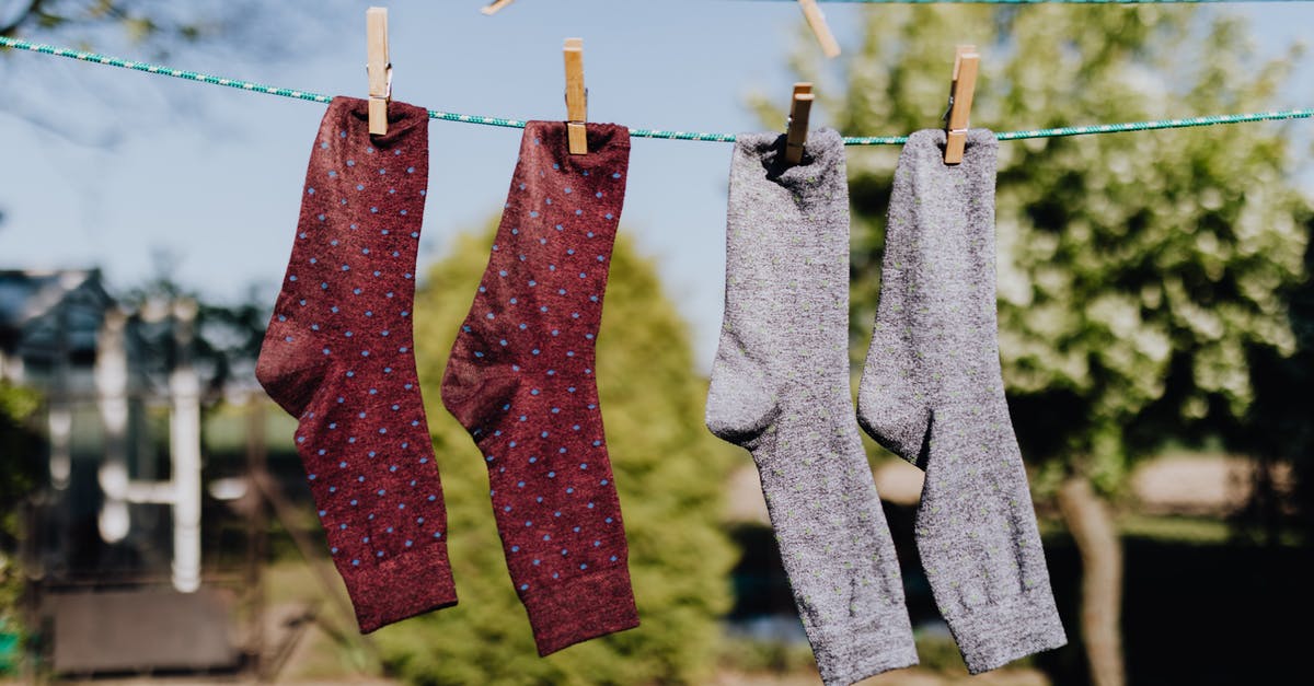 Molasses - dry vs. wet - Soft focus of washed multicolored socks hanging on rope with clothespins outdoors on sunny summer day against natural background