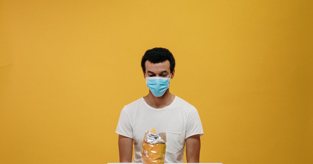 Mold on citrus: is it safe to eat? - Man in White Crew Neck T-shirt Wearing Blue Face Mask Sitting by the Table