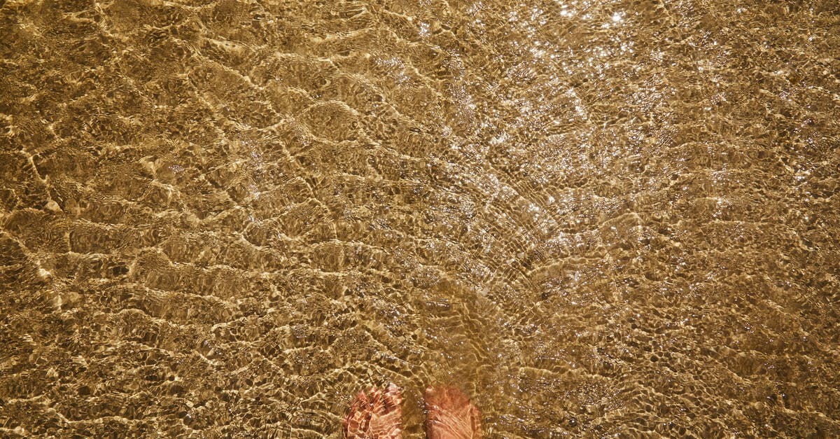 mousse with liquid in bottom - Top view of crop anonymous barefoot female standing in pure transparent rippling water of sea with sandy bottom