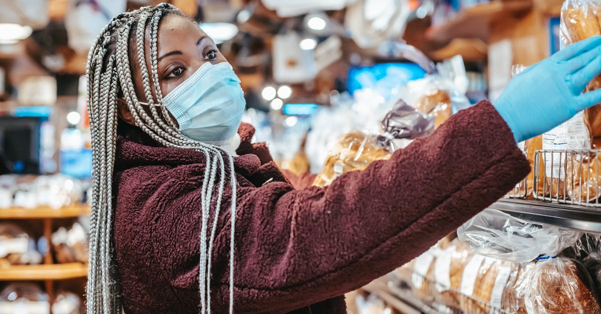 My applesauce has fermented, is it safe to bake with? - Side view of African American female buyer wearing medical mask and latex gloves choosing bread from shelf in supermarket