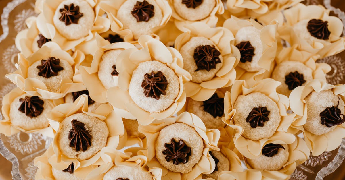 My soft chocolate cookies are soft but still too crumbly. How should I fix it? - Top view of tasty round shaped biscuits with chocolate cream in decorative flowers on transparent plate during festive event