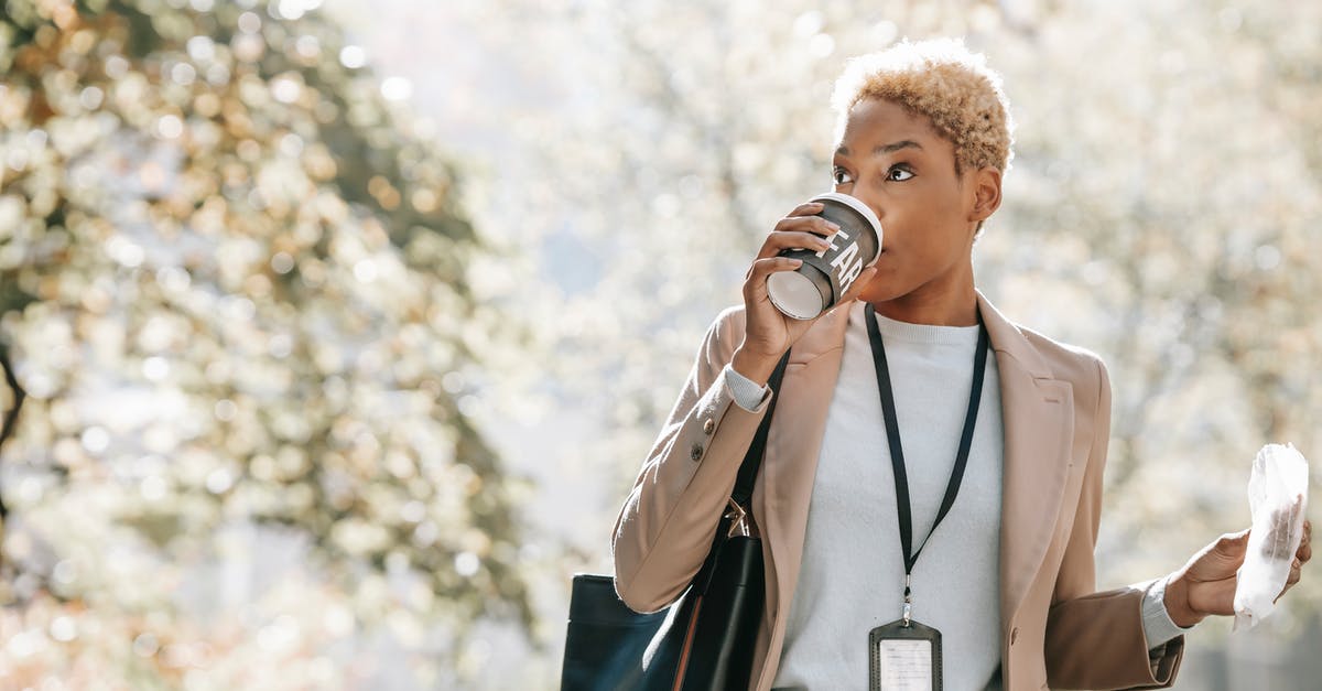 Name of the snack (possibly Indian) - Young African American businesswoman drinking takeaway beverage during coffee break in park