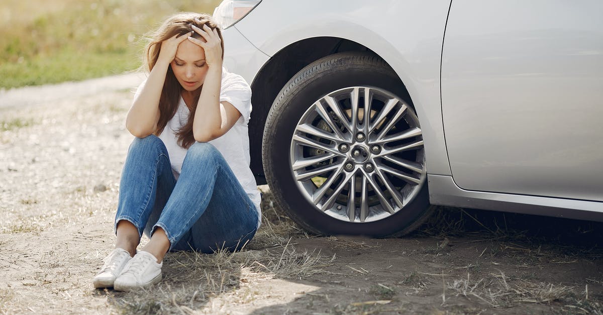 Need help choosing burner for wok - Frustrated female driver in white t shirt and jeans sitting on ground near damaged car with hands on head during car travel in sunny summer day