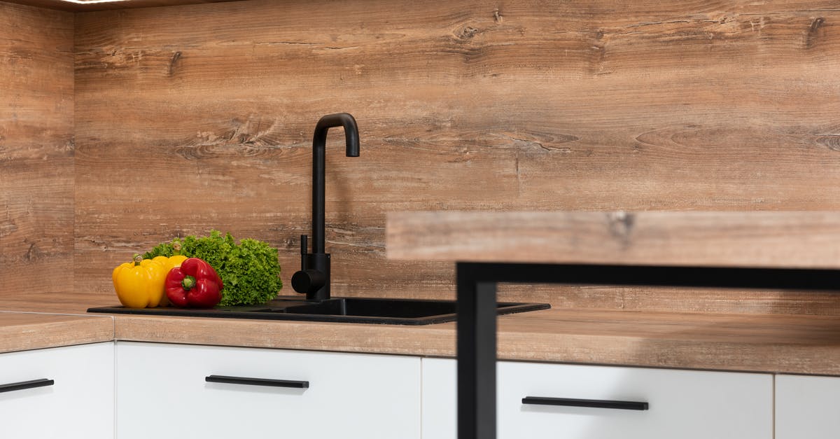 New green leaf vegetable in the family. What is it called? - Interior of contemporary kitchen with black sink and fresh green lettuce with colorful bell peppers