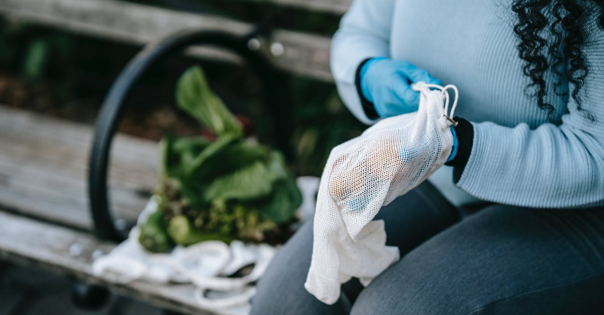 New green leaf vegetable in the family. What is it called? - Unrecognizable woman in gloves with eco friendly sack on street bench