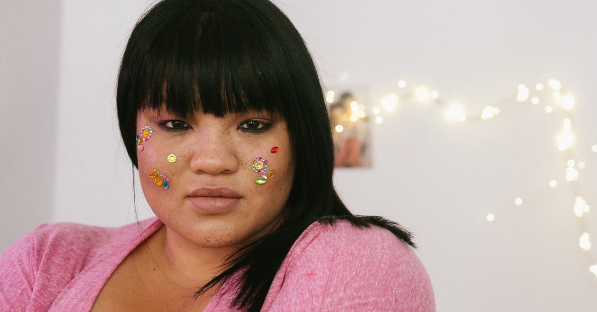 Not a tender steak - Tender young ethnic overweight lady with black hair and colourful glitter on face wearing pink shirt standing in light decorated room and looking at camera