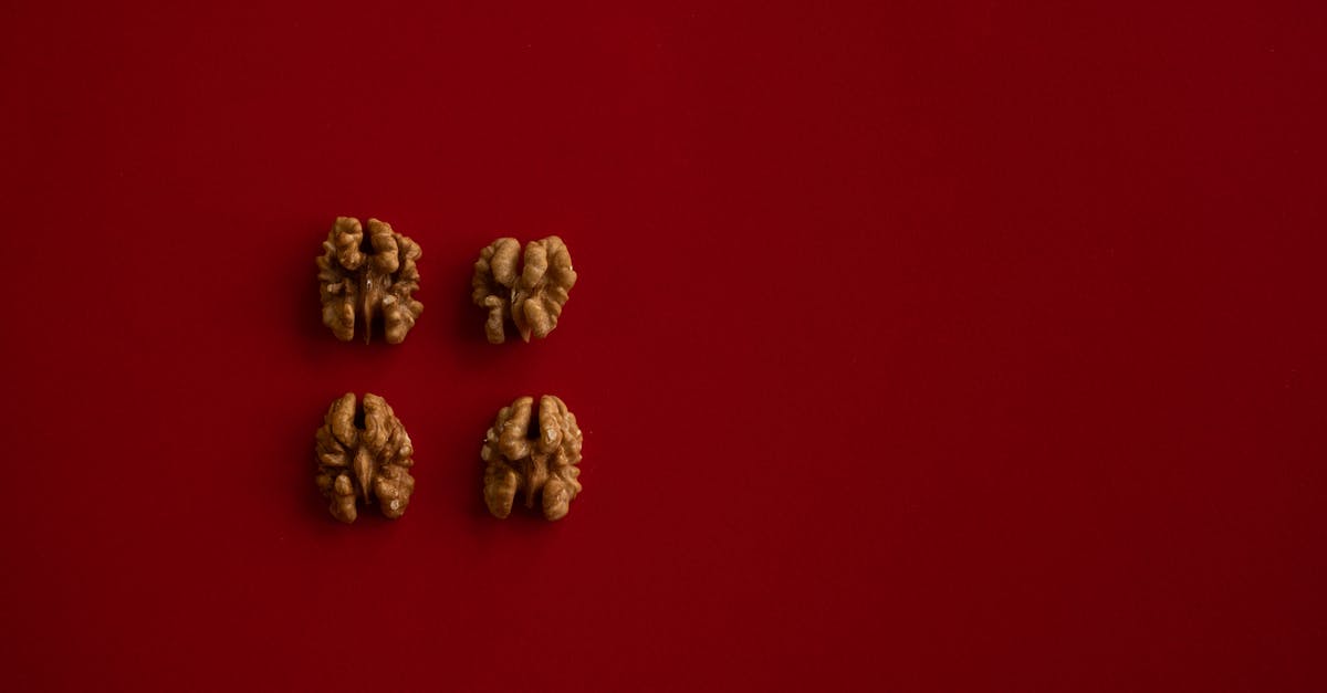 Nutrient composition of cheap cashews/nuts - Top view of halves of walnut kernel regularly placed on dark red background