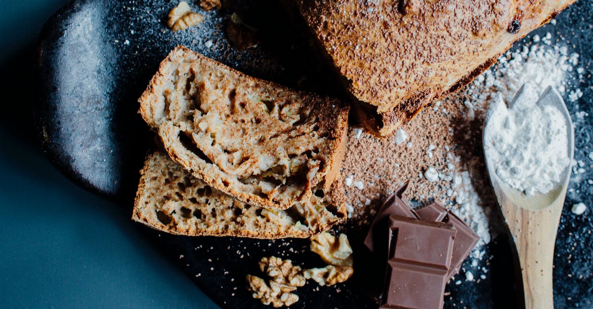 Nut/sunflower butter and cocoa - Top view of yummy banana bread with walnuts served on plate with chocolate bars and spoon of sugar powder