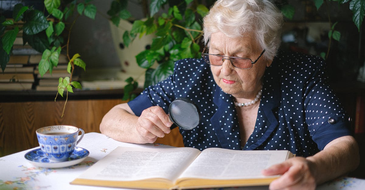 Old bread-slicing tool - Focused senior woman reading with magnifier