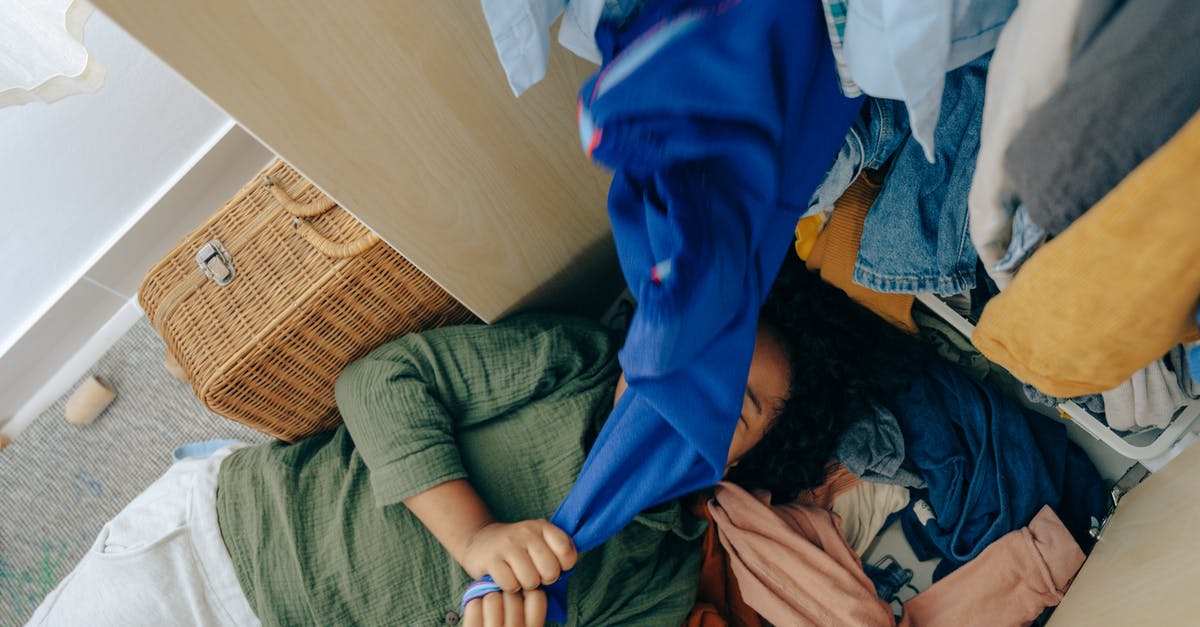 On-top-of-fridge storage - Anonymous black girl lying on stack of clothes in bedroom