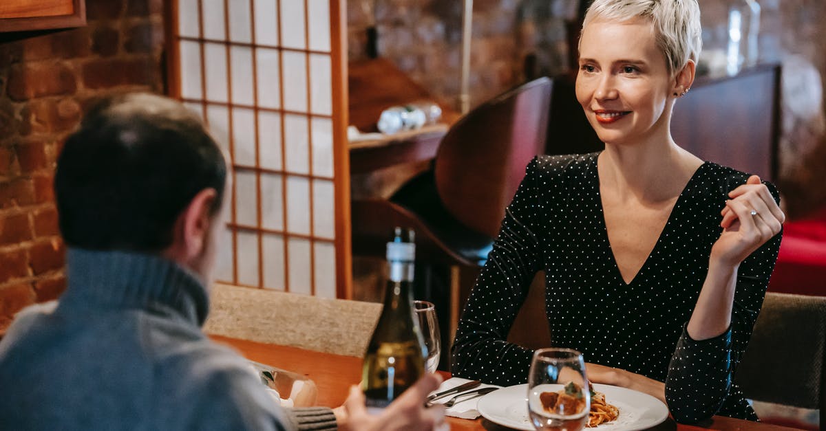 Opening wine bottle with rounded top using a waiter's friend - Couple having dinner with pasta and wine in room