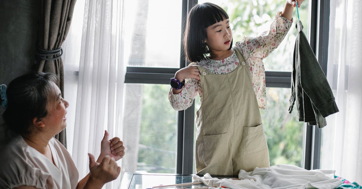 Oversalted and too matured kimchi (like sauerkraut)? - Happy Asian woman showing like gesture while granddaughter organizing clothes on hanger at home