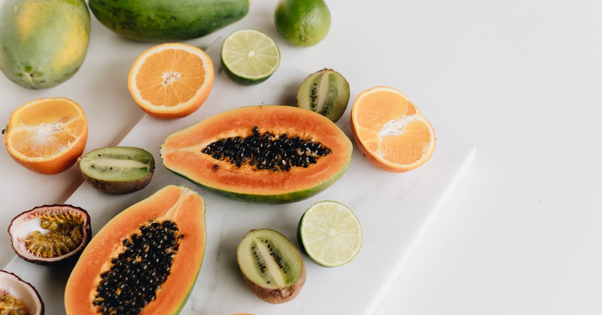 Papaya ripe or over ripe - Sliced Lemon and Black Berries on White Surface