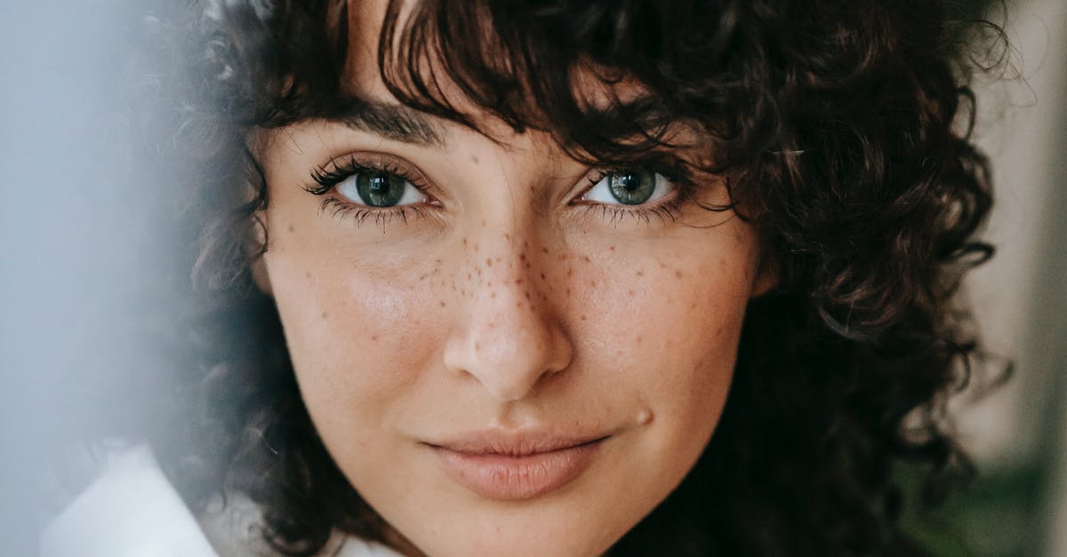 Parsley: flat-leaf or curly? - Headshot of attractive female with dark curly hair looking at camera against green leaves on blurred background in light room