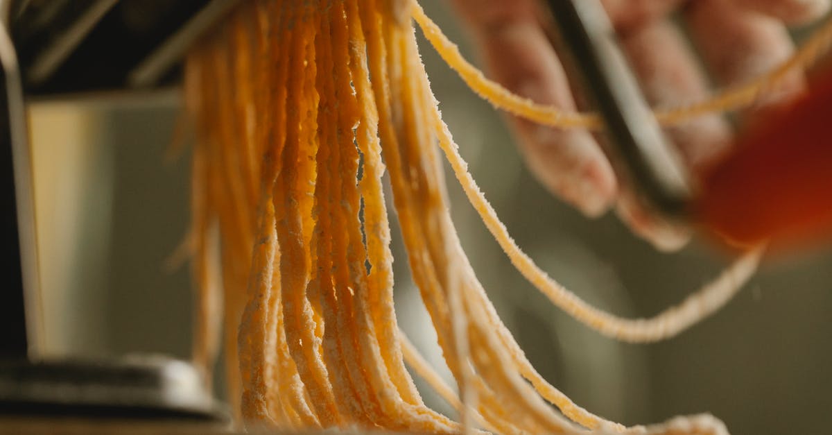 Pasta sticks to rolling cutters - Crop cook using pasta machine while preparing spaghetti