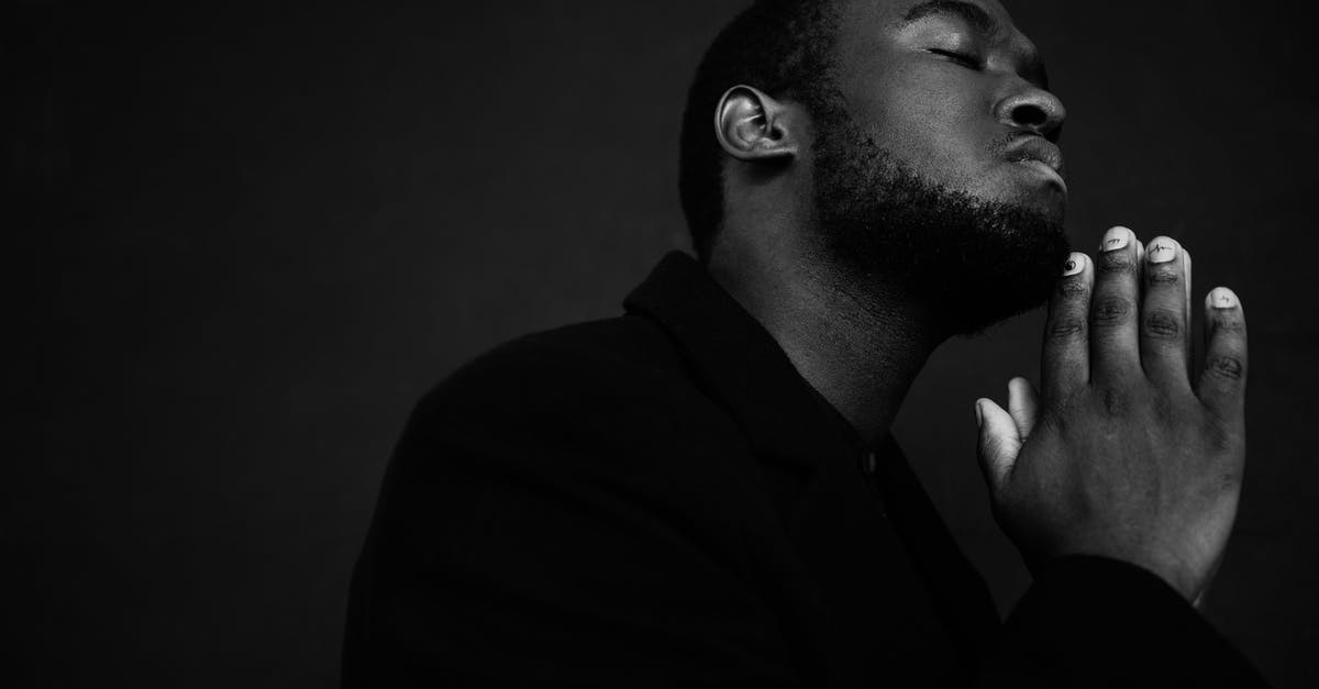 peeling black eyed peas for acaraje (fritters) - Monochrome handsome unshaven African American male in black suit praying with hands clasped under chin