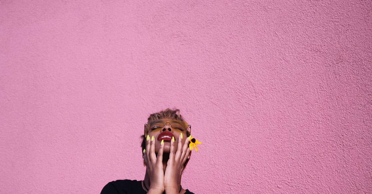 peeling black eyed peas for acaraje (fritters) - Stylish young African American female in casual wear and sunglasses with closed eyes touching face while throwing head back on pink background