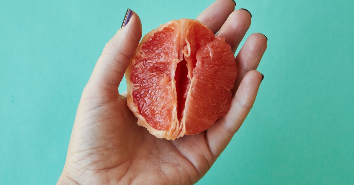 Peeling very ripe plantains? - From above of crop anonymous female demonstrating half of juicy peeled grapefruit as vagina against blue background in studio