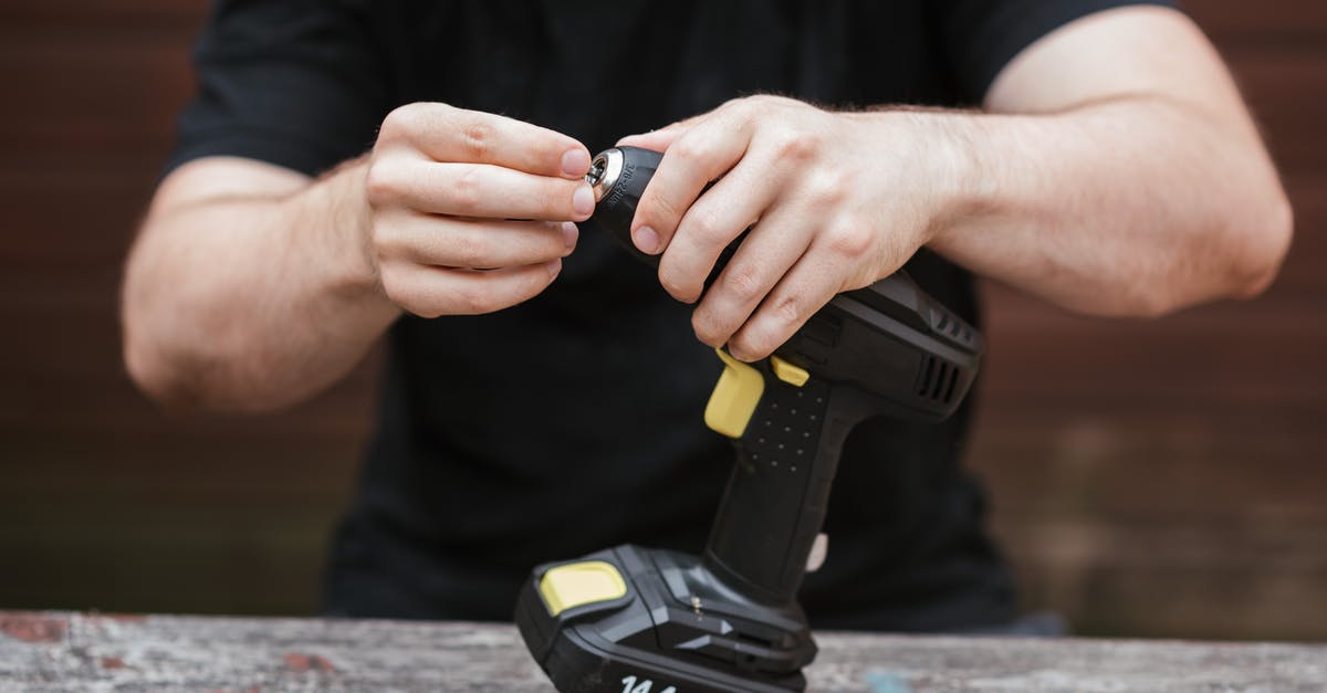 Pemmican -- how was it prepared without metal tools? - Crop anonymous skilled master in casual outfit preparing electric drill for job on wooden table in soft daylight