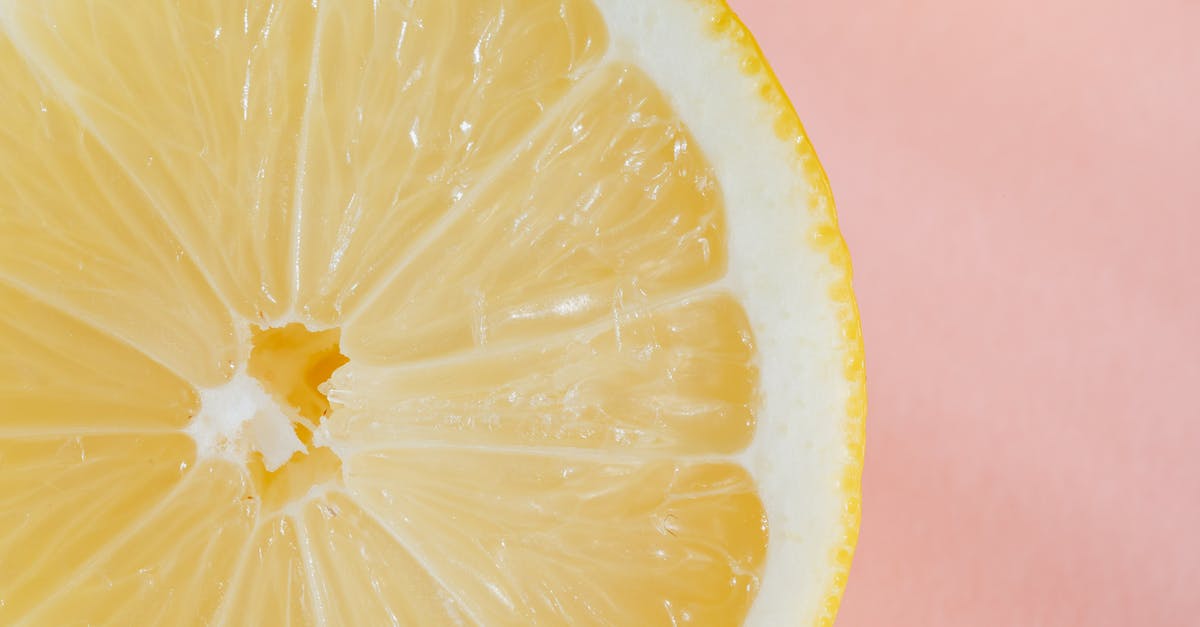 PH and sour / acid taste - Closeup of slice of fresh juicy bright lemon placed on smooth pink surface