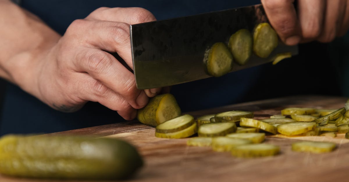 Pickling whole cucumbers - Person Slicing Pickles on a Wooden Chopping Board