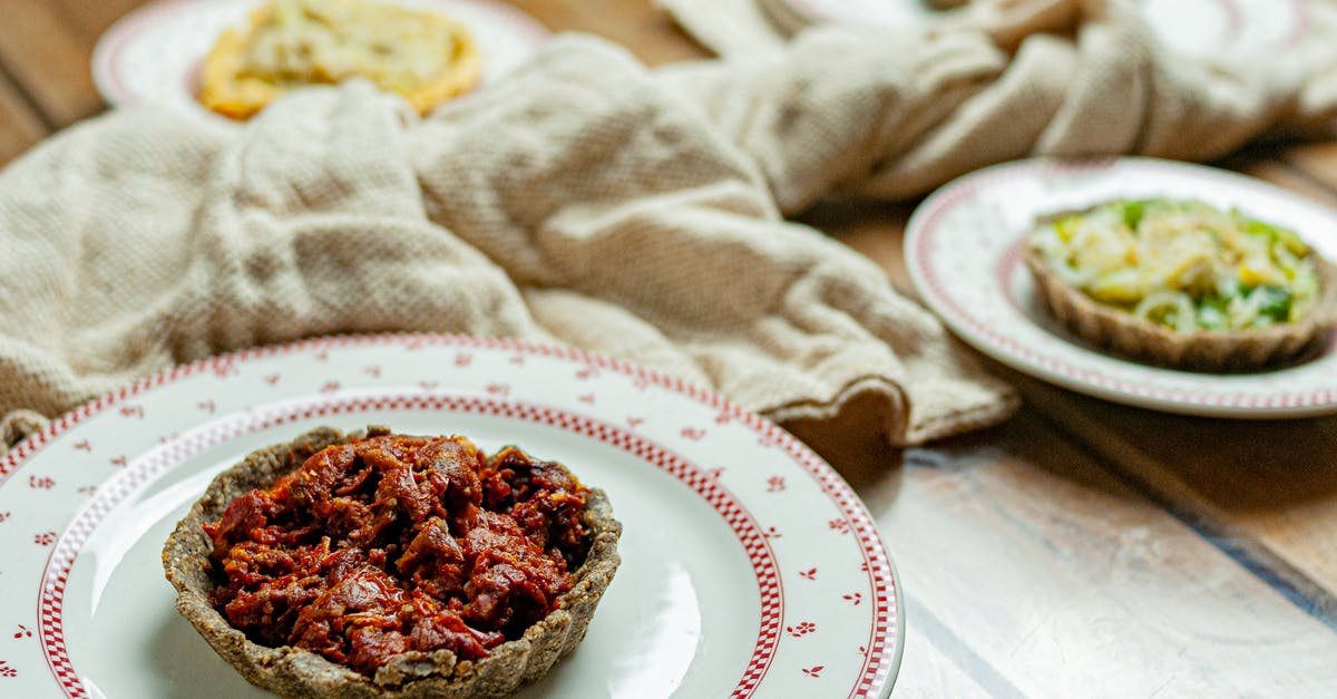 Pie Crust Partially Cooked - High angle of tasty homemade tart with dried tomatoes and pepper in plate on wooden table