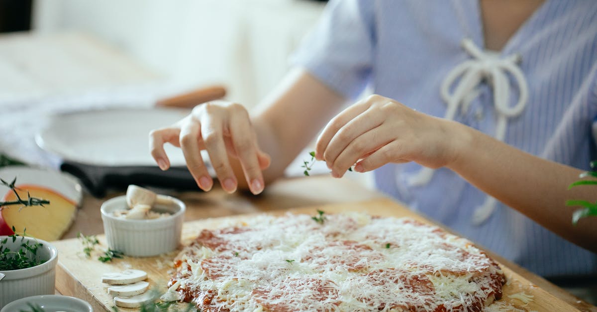 Pizza dough didn't rise, maybe yeast cells were killed off - Woman making pizza in kitchen