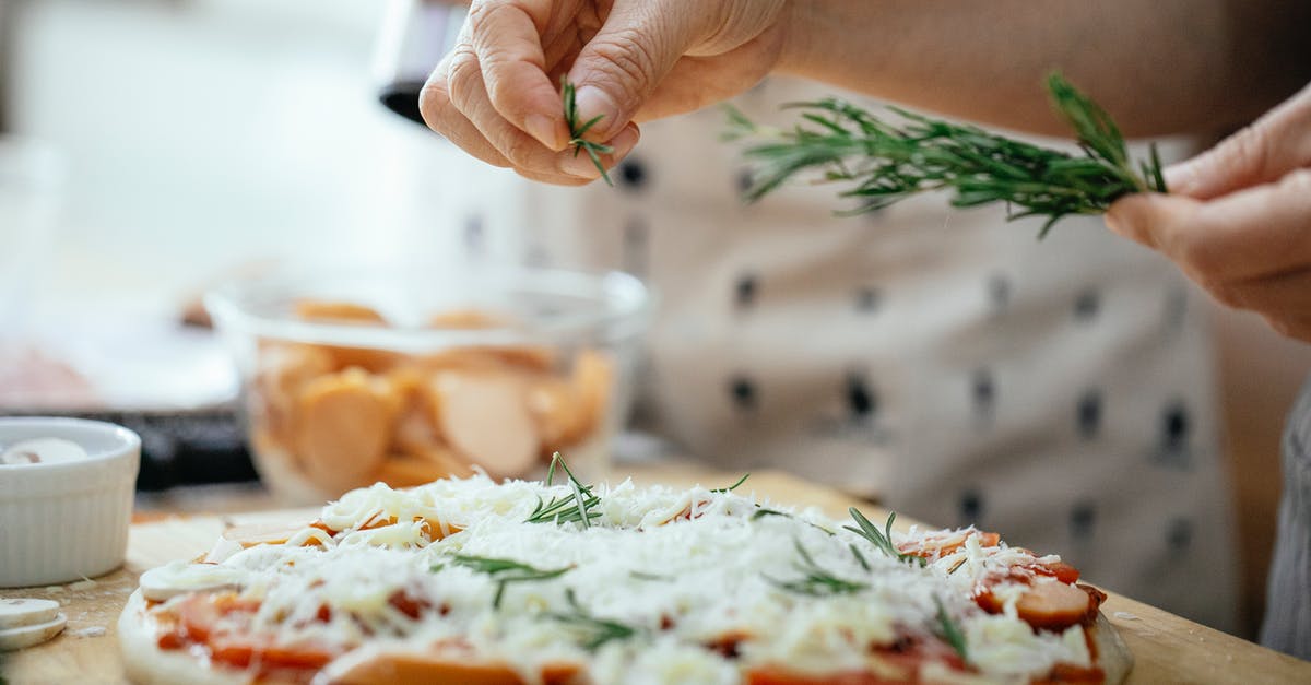 Pizza dough is too soft to stretch well - Crop person seasoning pizza with rosemary