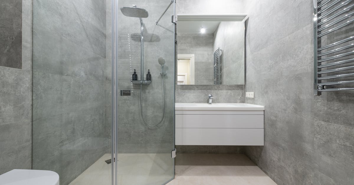 Placing a ceramic bowl over stainless steel saucepan - Modern shower room interior with glass walls against washstand