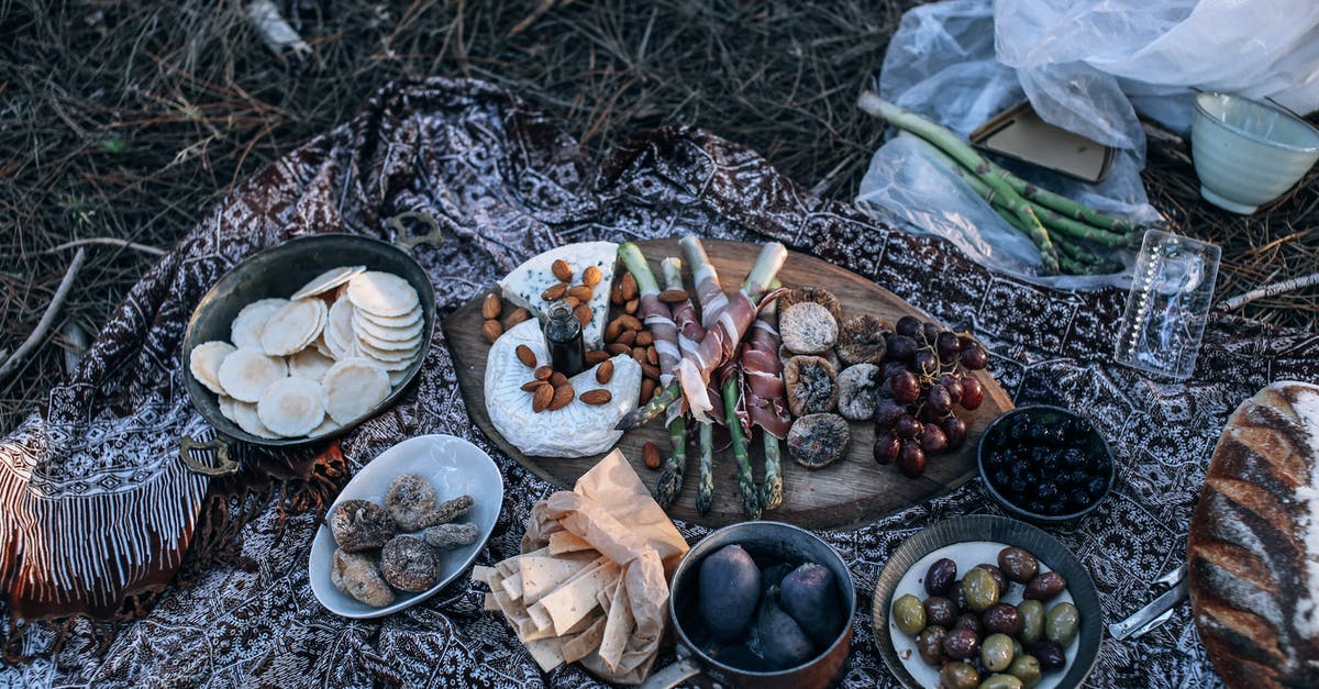 Please identify this nut covered cheese - From above of appetizing homemade bread and cheese placed near fruits and vegetables in bowls and on wooden cutting board for picnic on nature