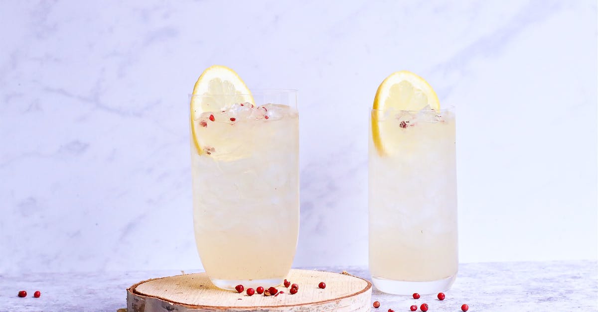 Plums are sour. Why are prunes sweet? - Glasses of delicious cold lemonade decorated with lemon slice and berries on wooden board in light studio