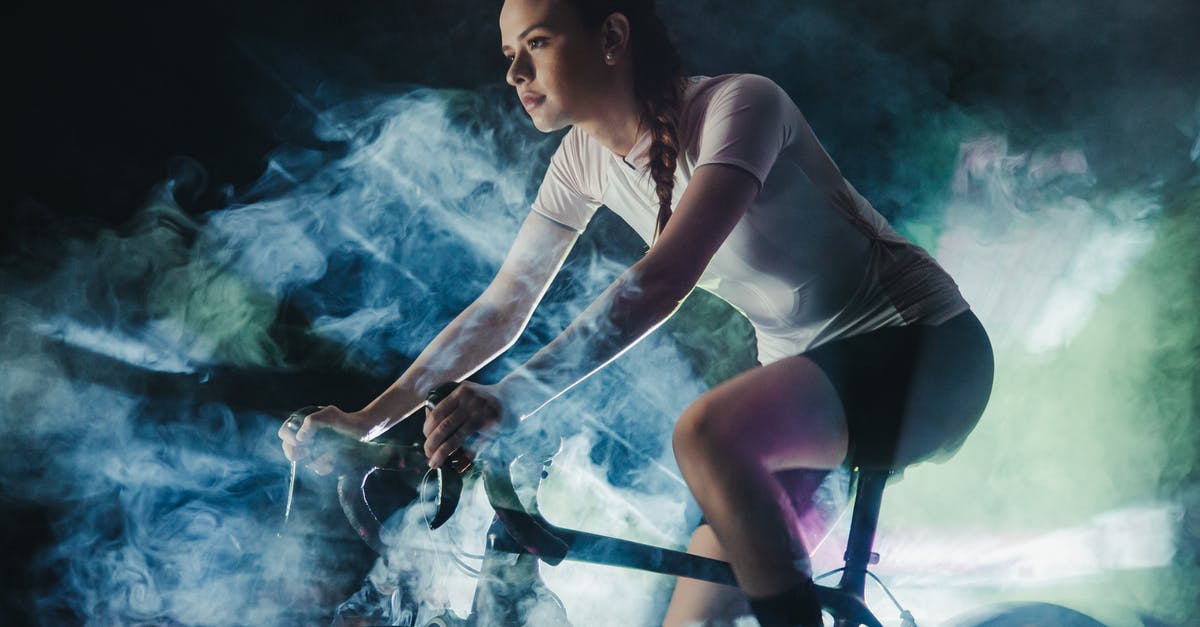 Polymer fume fever probably detected - Young female athlete in active wear with concentrated gaze riding bicycle in shiny cloud while looking forward