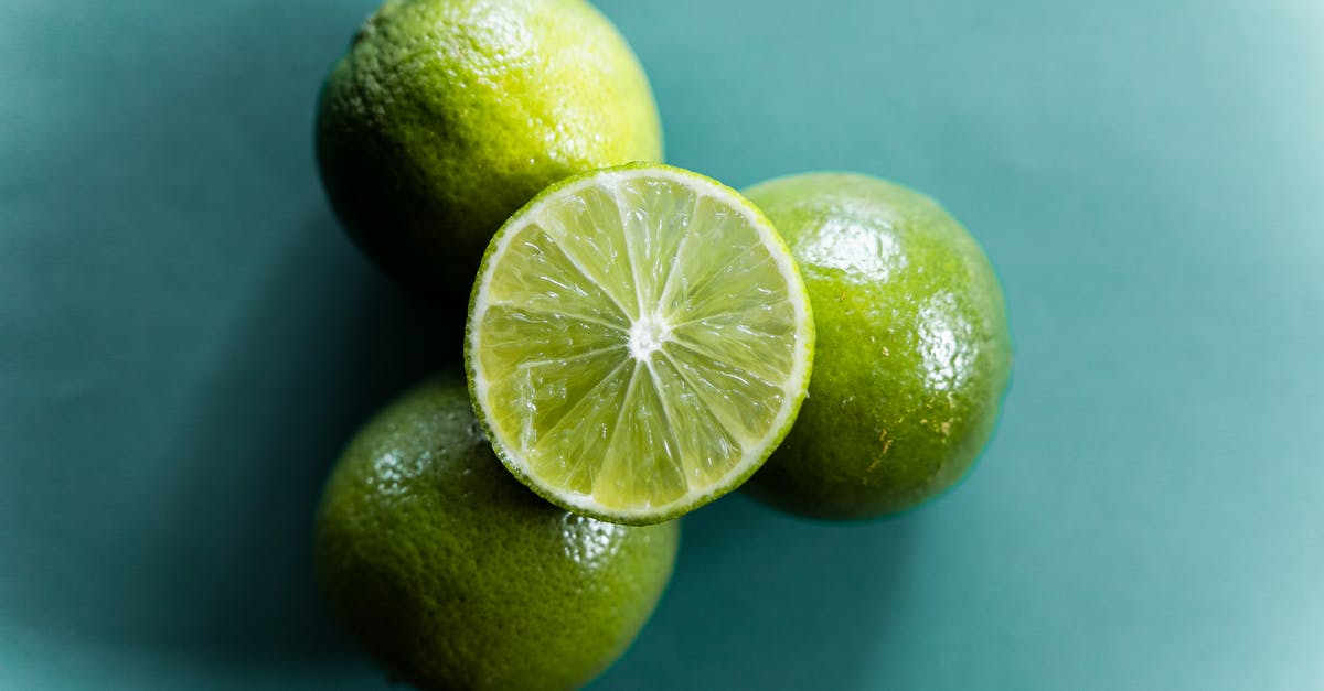 Post harvest treatment of organic limes vs conventional limes - Top view of fresh ripe halved and whole limes stacked on green background