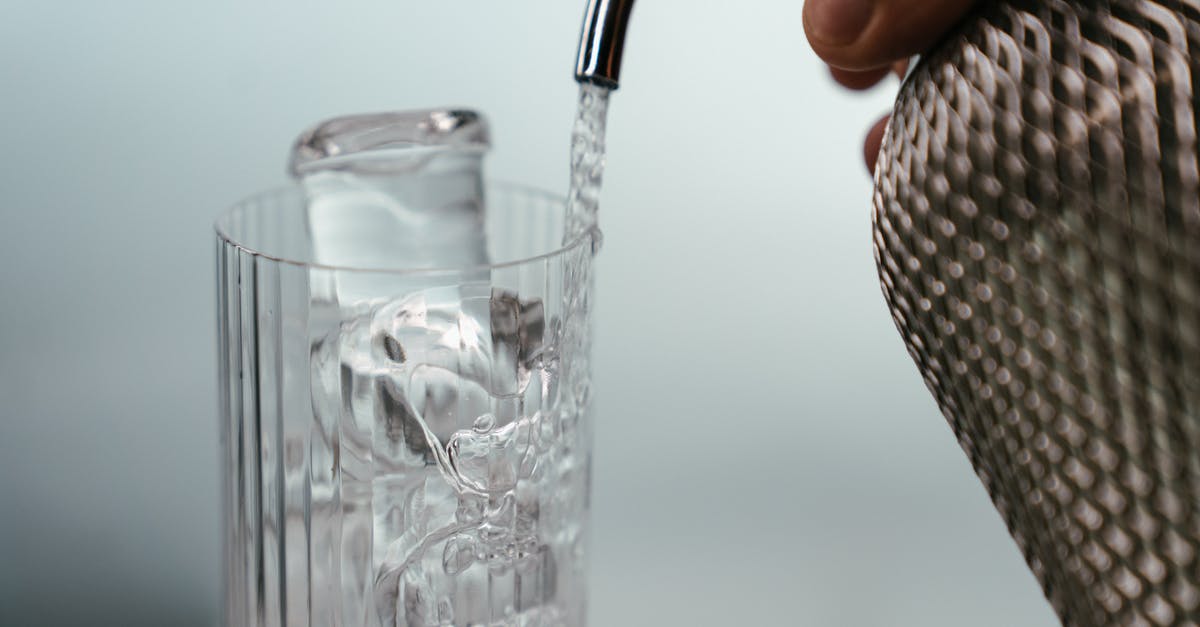 Pouring cold water on pasta after cooking it - Person Holding Clear Drinking Glass