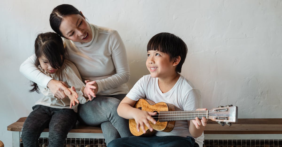 Practical home stone grinding [duplicate] - Dreamy ethnic brother in casual wear playing Hawaiian musical instrument while looking up and sitting near little sister and mother on wooden bench