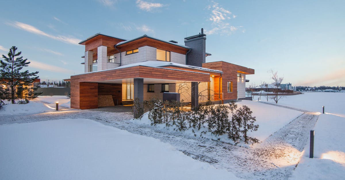 Practical home stone grinding [duplicate] - Exterior view of luxurious residential house with roofed parking and spacious backyard in snowy winter countryside