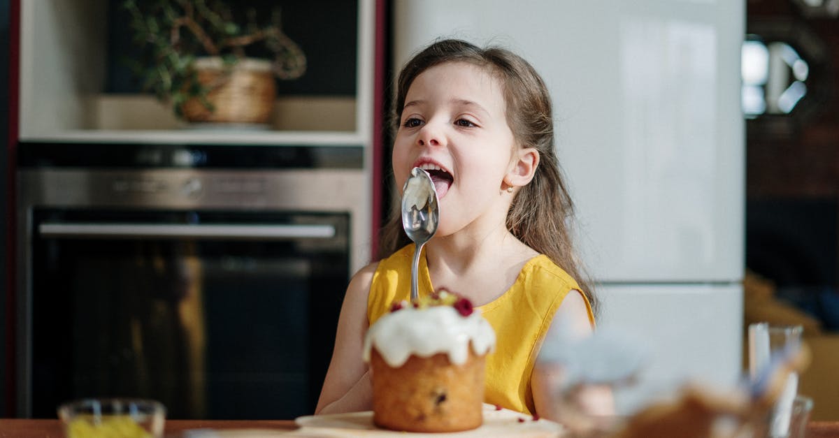 Pre-frosting cake with jelly - Girl in Yellow Shirt Licking Icing on Spoon