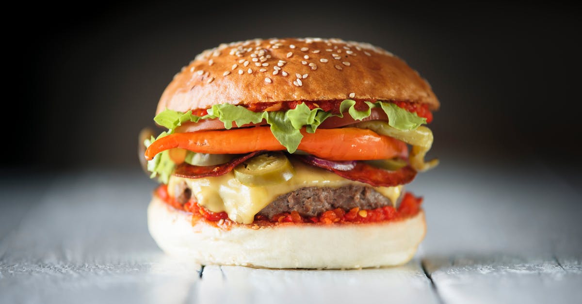 Preparing Salsa Verde fast and fresh - Tasty burger with vegetable slices between buns on dark background