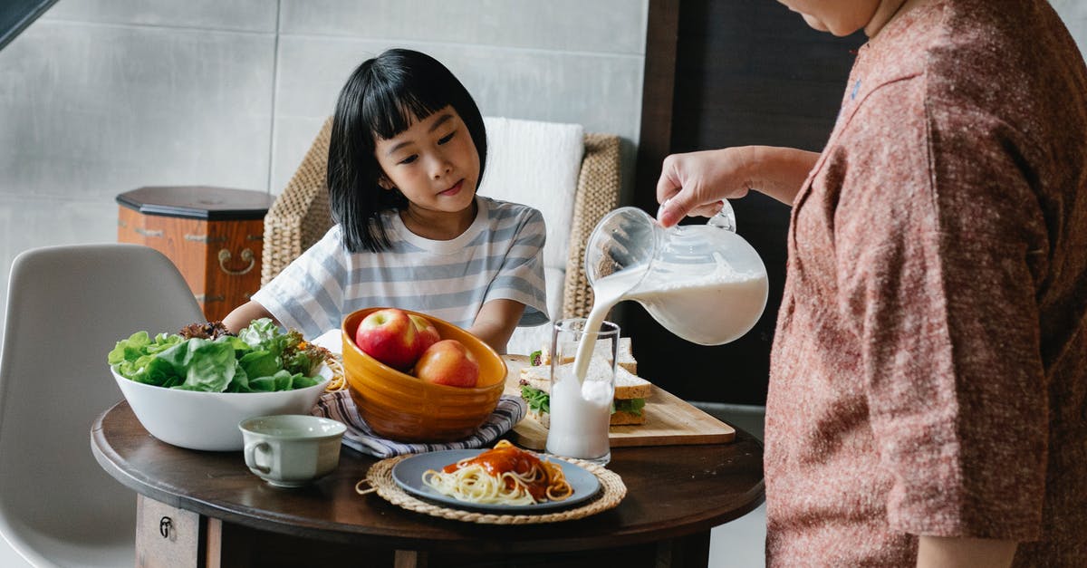 Preparing soy milk at home - Crop faceless female standing near table and preparing healthy lunch for cute Asian kid at home