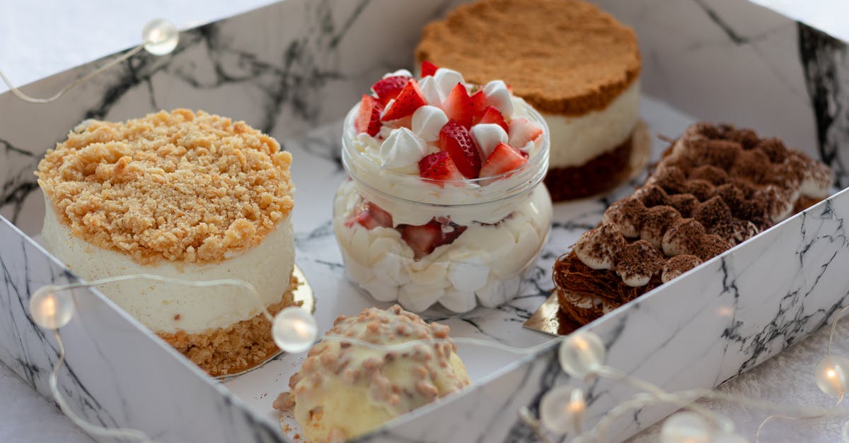 Presentation - How to make a Tiramisu to be photogenic? - From above of delicious sweet cupcakes including creamy parfait with strawberry and round honey cake and napoleon cake near plate with tiramisu and cupcake covered with white chocolate placed in white box