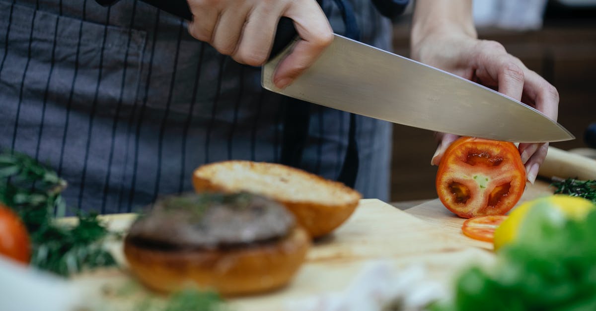 Preserve crustiness/freshness of toasted bread - Unrecognizable female cook cutting fresh tomato with knife while standing at table with toasted buns on wooden cutting board while cooking against blurred background