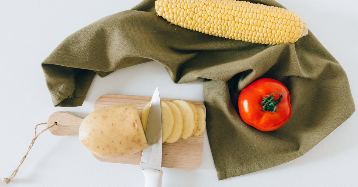 Preserving whole potatoes - Slices of Potato on a Wooden Chopping Board Beside a Tomato and Corn
