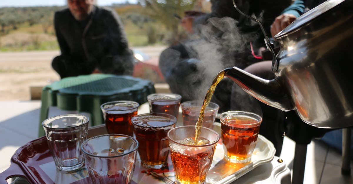 pre-soaking tea in cold water prior to brewing - Man pouring tea from kettle into glass cups